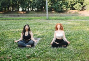 twee vrouwen mediteren in gras