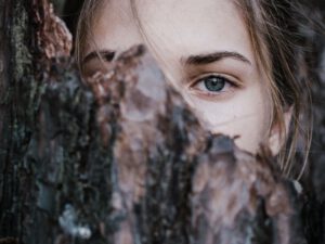 vrouw verschuilt achter boomschors