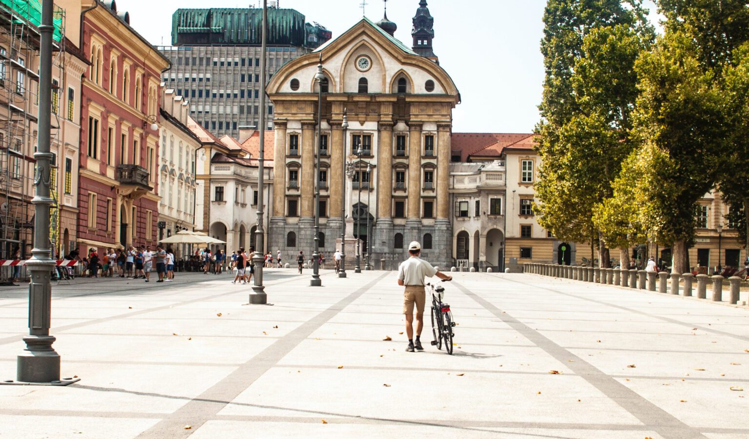 man loopt met fiets aan de hand over plein in Ljubljana.